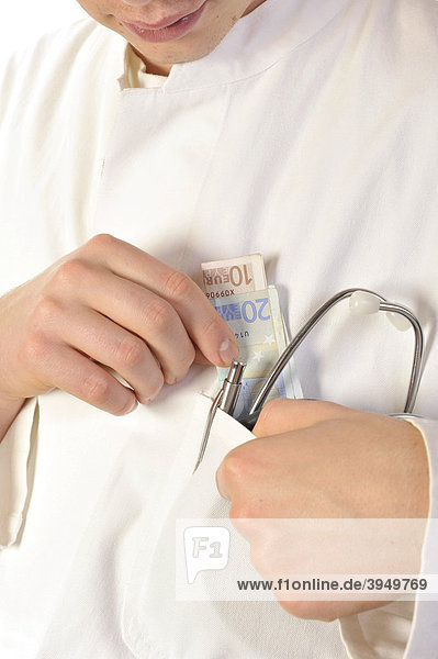 Arzt steckt Geldscheine in seine Kitteltasche