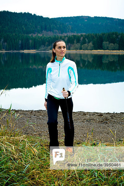 Young woman doing nordic walking beside a lake