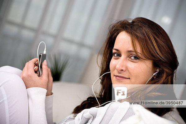 Young woman listening to music on MP3 player