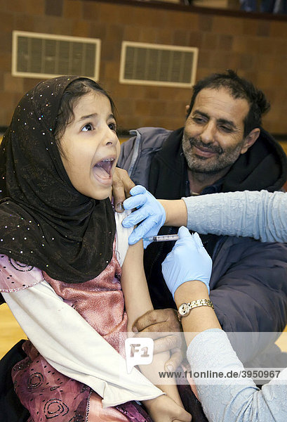 A health care worker vaccinates a girl against the H1N1 swine flu as her dad watches  Hamtramck  Michigan  USA