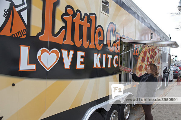 Eine Frau bekommt eine kostenlose Pizza aus der mobilen Little Caesars Love Kitchen  die vor der Suppenküche der All Saints Catholic Church parkt  betrieben von der Little Caesars Pizza-Kette  Detroit  Michigan  USA