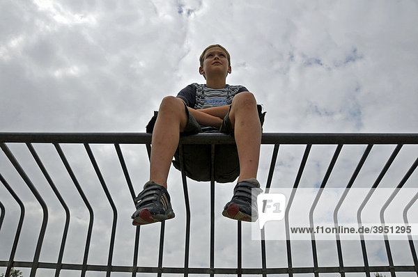 Einsamer neunjähriger Junge auf einem Metalltor  Bolzplatz in Köln  Nordrhein-Westfalen  Deutschland  Europa