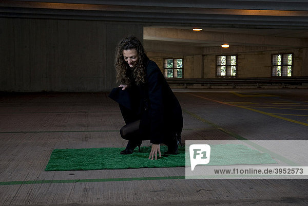 Woman in empty concrete car park on artificial grass