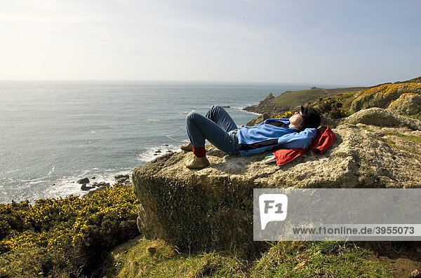 Frau liegt auf Stein  Rast  Pause  Wandern  Küste  Meer  Cornwall  Südküste  Südengland  England  Großbritannien  Europa