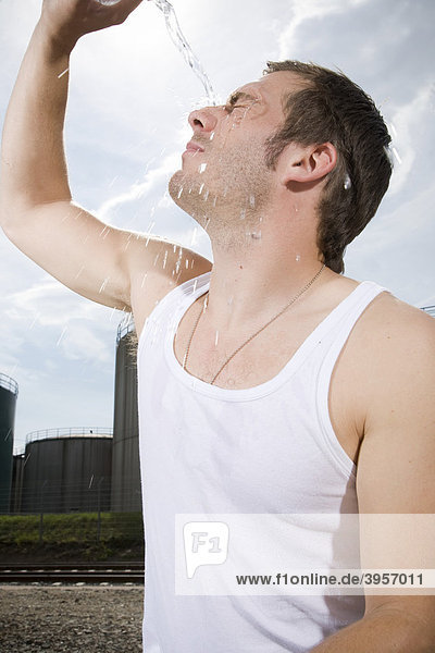 Young man tipping water onto his face