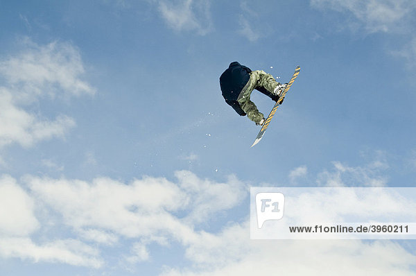 Snowboarder jumping  against blue clouded sky