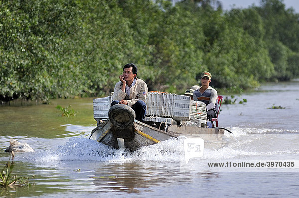 Two men riding on a wooden market boat in a side channel of the Mekong River  Mekong Delta  Vietnam  Asia