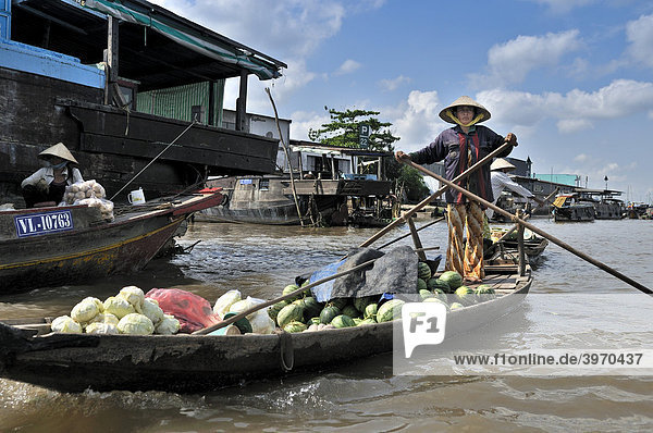 Frau mit traditionellem Hut  Kegelhut aus Palmenblättern  rudert stehend ein Holzboot am Mekong  Ladung von Obst und Gemüse  Mekongdelta  Vietnam  Asien