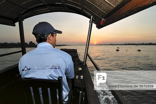 Ein Bootsfahrer von hinten blickt Richtung Sonnenaufgang  Mekongdelta  Vietnam  Asien