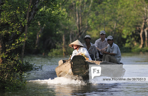 Eine Frau mit traditionellem vietnamesischem Kegelhut fährt ein Boot auf dem Mekong  hinten drei Männer  Vinh Long  Mekongdelta  Vietnam  Asien