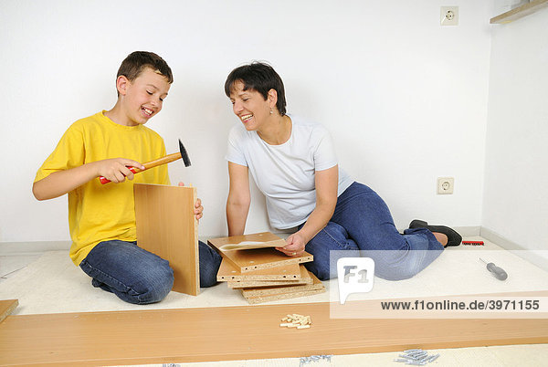 Mutter und Sohn beim Möbel zusammenbauen  Montage Regal-Brett