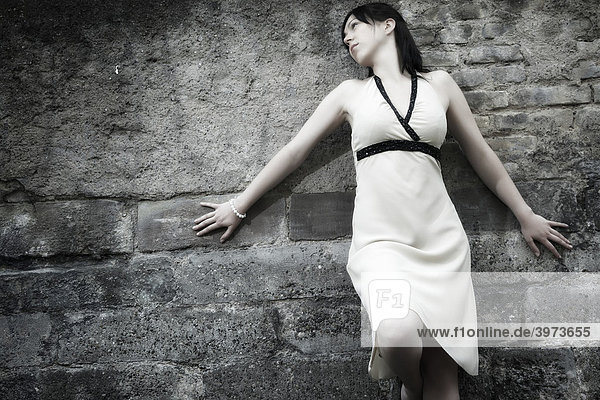 Portrait einer jungen dunkelhaarigen Frau vor einer Steinwand