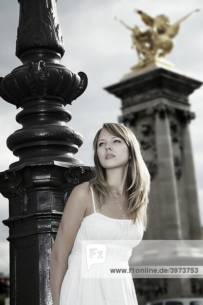 Portrait einer jungen dunkelblonden Frau im weißen Kleid angelehnt an eine Straßenlaterne Alexanderbrücke Paris Frankreich Europa