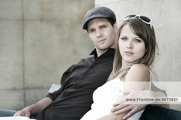 Junges Paar sitzt gemeinsam auf einer Parkbank