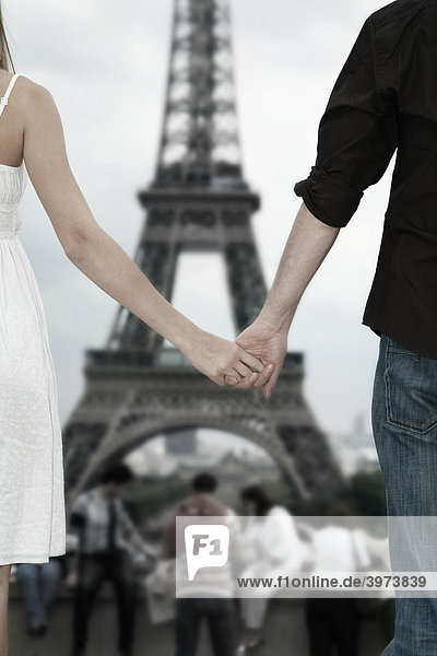 Junges Paar Hand in Hand vor dem Eiffelturm  Paris  Frankreich  Europa