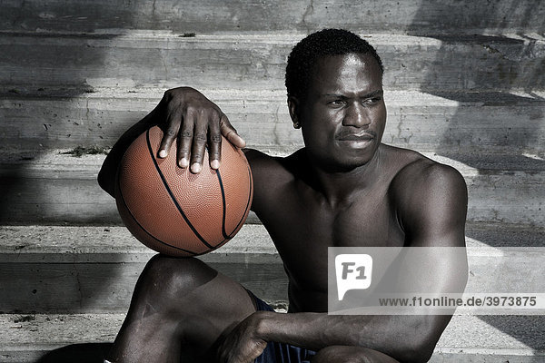 Dark-skinned basketball player sitting on stairs portrait