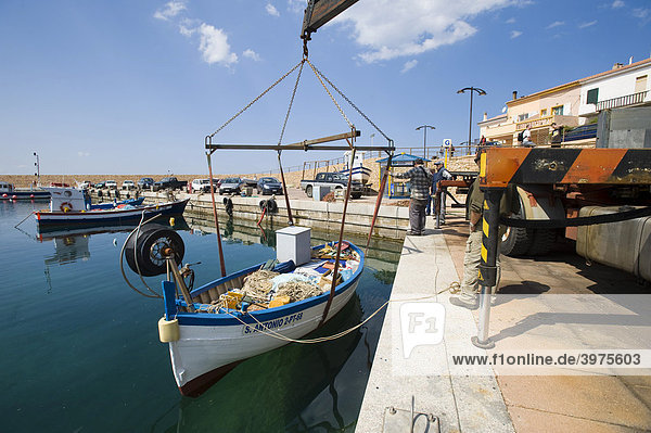 Fischerboot wird mit einem Kran ins Hafenbecken abgelassen  Isola Rossa  Sardinien  Italien  Europa