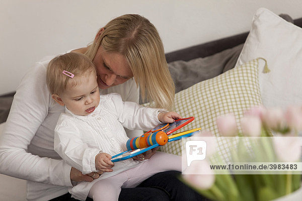 Mutter liest Buch mit ihrer Tochter  1-jährig