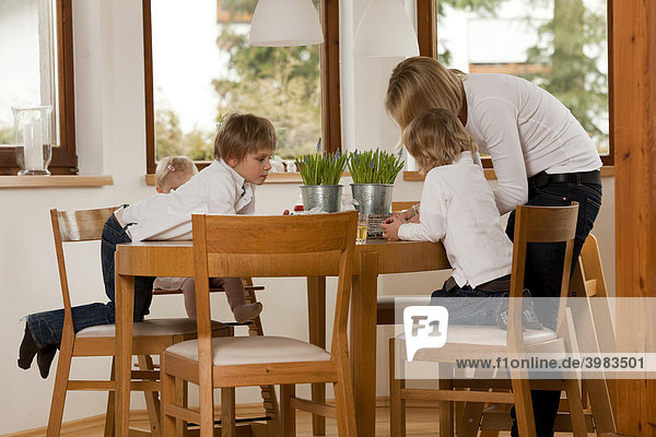 Mother and three children  1  3 and 6 years old  at the dining table