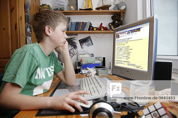 Junge  13 Jahre alt  surft mit seinem Computer zuhause im Internet auf einer Lernseite für Schüler Englisch Lektionen online