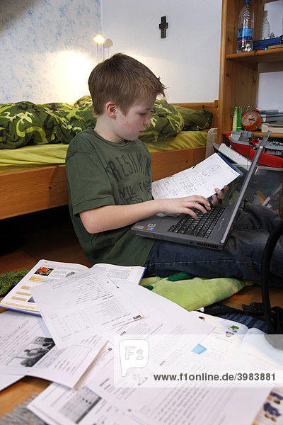 Boy  11  working with his computer at home in his bedroom doing school homework