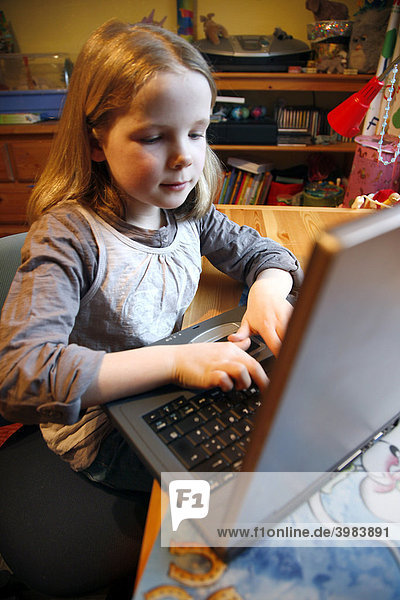 Girl  7 years old  working with a computer at home in her room  doing homework for school  educational software