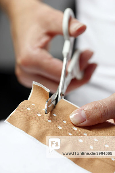 Adhesive bandage is being cut to treat a small wound
