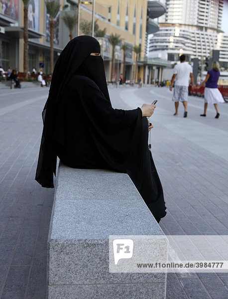 Arabische Frau im klassischen schwarzen Gewand  der Abaya  mit Handy  im Einkaufszentrum Dubai Mall  Dubai  Vereinigte Arabische Emirate  Naher Osten