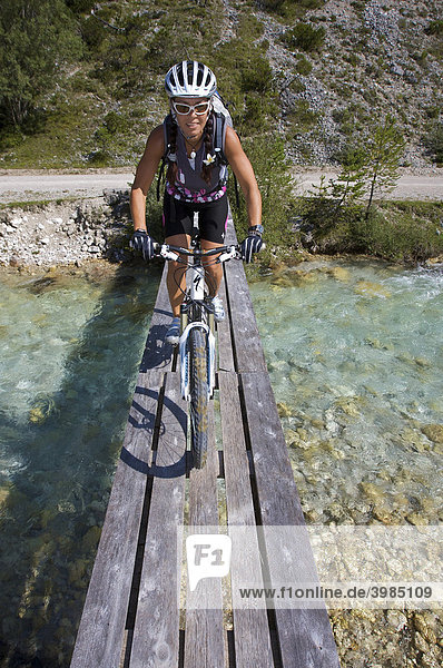 Mountainbike-Fahrerin auf schmaler Holz-Brücke über die Isar südöstlich von Scharnitz  Tirol  Österreich