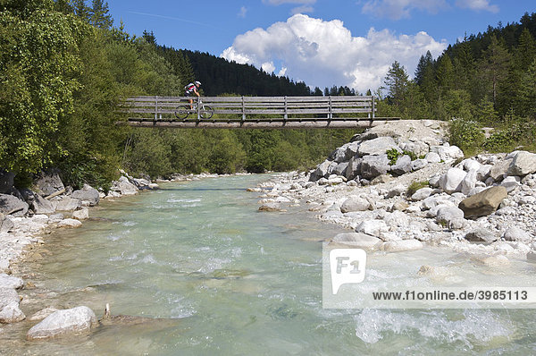 Female mountainbike rider crossing a narrow wooden bridge over Leutascher Ache River  Gaistal Valley  Leutasch  Tyrol  Austria  Europe