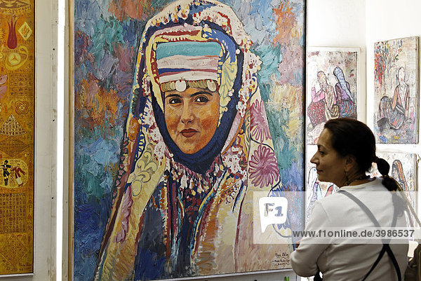Frau betrachtet Gemälde einer anatolischen Frau in traditioneller Tracht  Kunstgalerie  Sultanahmet  Istanbul  Türkei