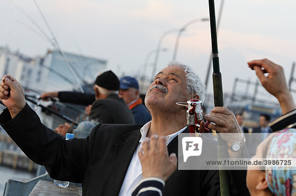 Weißhaariger türkischer Angler begutachtet seinen Fang an der Angel  Galata-Brücke  Eminönü  Istanbul  Türkei