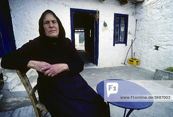 Alte  schwarz gekleidete griechische Bäuerin mit abgearbeiteten Händen  sitzt im Hof ihres Hauses  Porträt  Elounta  Nordküste  Kreta  Griechenland  Europa