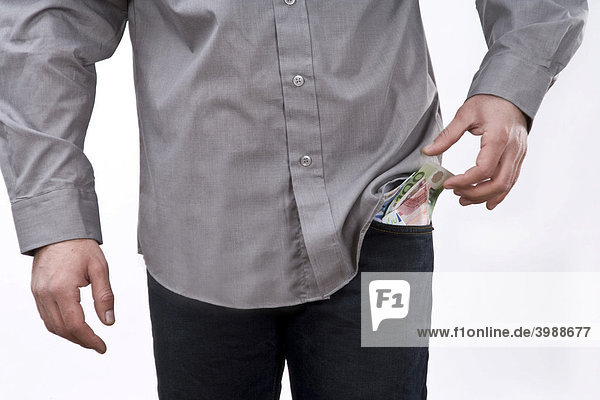Euro banknotes sticking out of the trouser pocket of a young man
