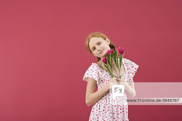 Rothaariges Mädchen mit Zöpfen und Sommerkleid vor Rot mit Blumen