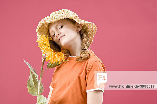 Rothaariges Mädchen mit Zöpfen  Strohhut und Sonnenblume vor Rot