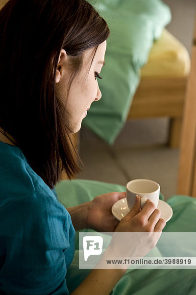 Junge Frau mit Kaffee im Bett