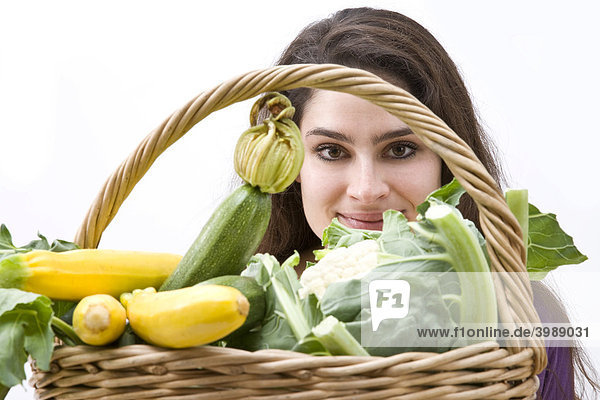 Mädchen blickt durch Gemüsekorb