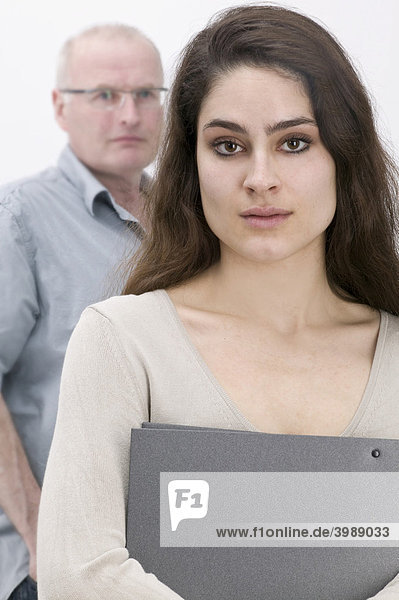 Girl holding a file  serious looking man in the back
