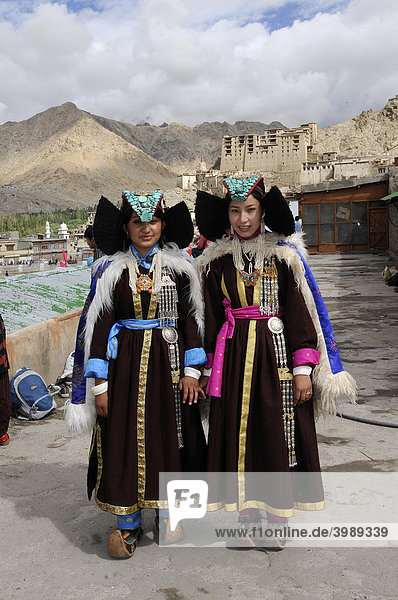 Ladakhi in traditioneller Kleidung mit Perak  Kopfbedeckung mit Türkisen  im Hintergrund der Palast  Leh  Ladakh  Himalaja  Nordindien  Indien