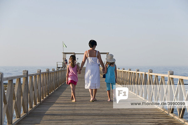 Mother and two daughters walking on a jetty