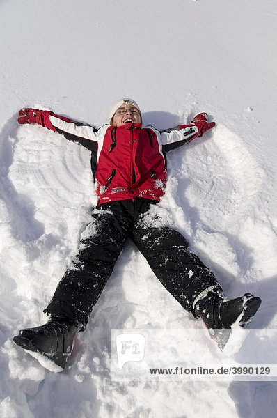 Mädchen  acht Jahre  produziert Schneeengel im Schnee