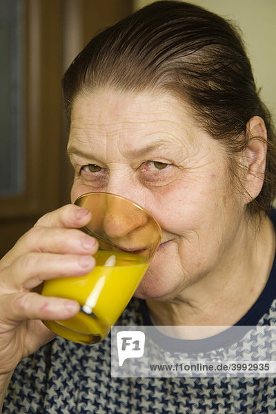 67 Jahre alte Frau trinkt Orangensaft