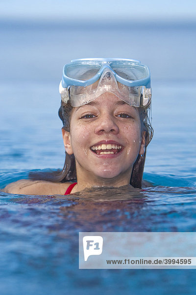 Mädchen mit Taucherbrille im Schwimmbad  lacht in die Kamera