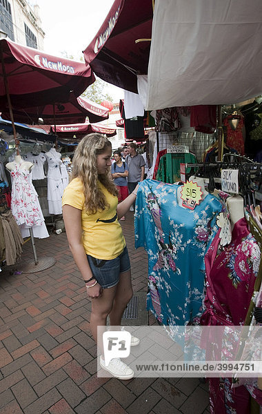 Touristin interessiert sich für ein Kleid  Chinatown  bunter Markt als Touristenattraktion  Temple street  Singapur  Südostasien