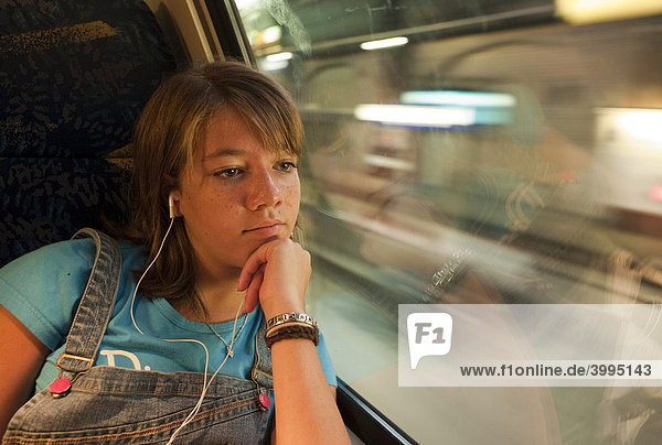 Mädchen sitzt alleine in einem in einem Zug und sieht aus dem Fenster  Deutschland