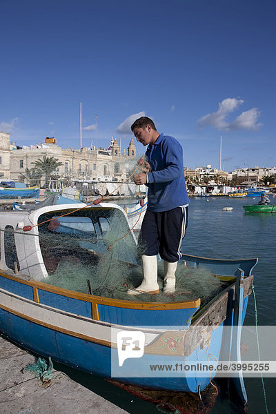Fischer repariert sein Netz auf einem Fischerboot  Hafen von Marsaxlokk  Malta  Europa