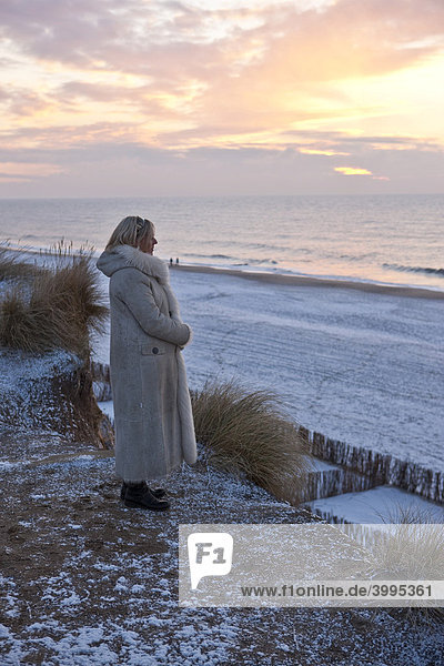 Sylt im Winter  Frau steht am Roten Kliff und schaut den Sonnenuntergang an  Kampen  Sylt  nordfriesische Insel  Schleswig-Holstein  Deutschland  Europa