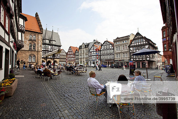 Touristen sitzen auf dem Marktplatz mit dem Rathaus und dem Weinhaus  Altstadt  Alsfeld  Hessen  Deutschland  Europa