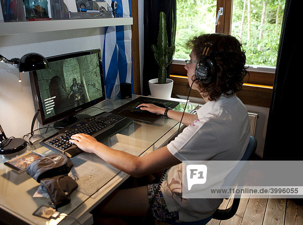 A boy  about 15  playing a violent game on the computer in his room  Germany  Europe